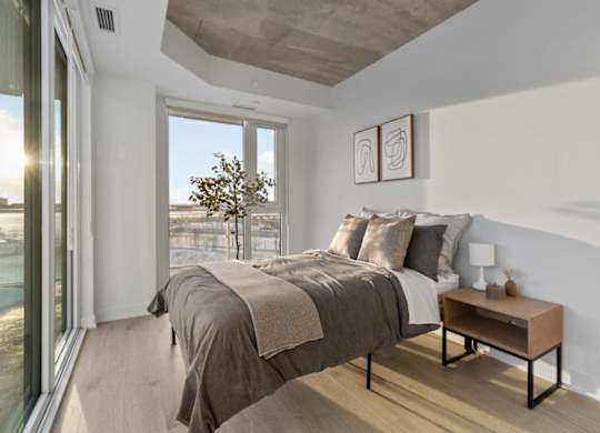 A bedroom with a large bed and a small table by the window.