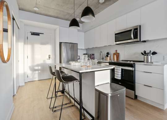 A modern kitchen with white cabinets and a wooden floor.