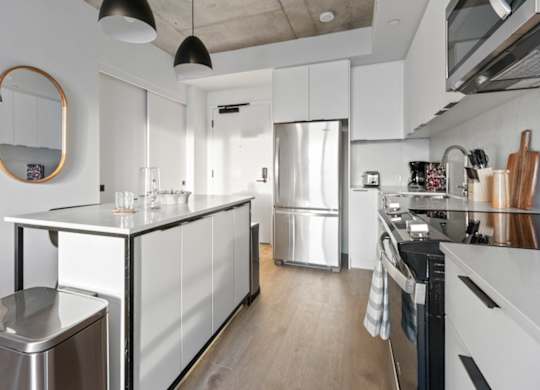 A modern kitchen with a stainless steel refrigerator and wooden floors.