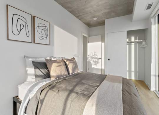 A bedroom with a large bed and two abstract art pieces on the wall.