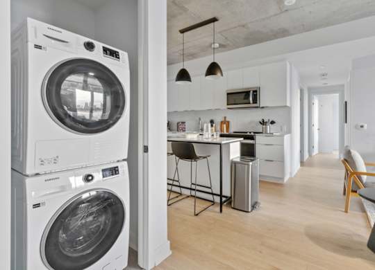 A white washing machine is stacked on top of another in a modern kitchen.