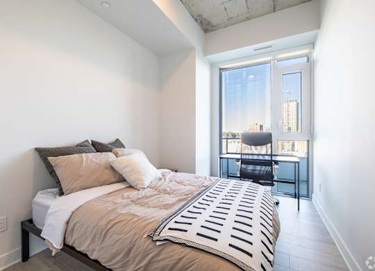 A bedroom with a large bed and a desk with a chair.