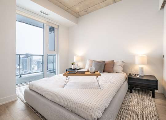 A bedroom with a large bed and a window overlooking a cityscape.
