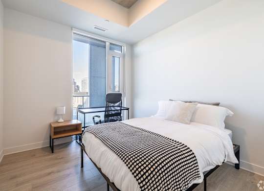 A bedroom with a bed, chair, and window.