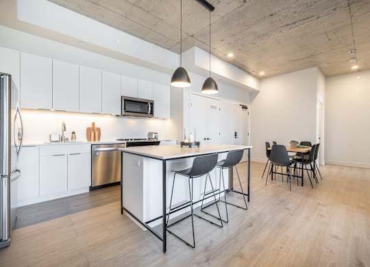 A kitchen with a white counter and black barstools.