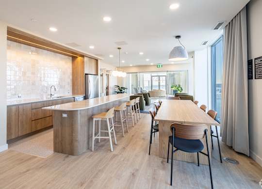 A modern kitchen with a long wooden table and chairs.