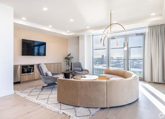 A modern living room with a large window and a flat screen TV mounted on the wall.