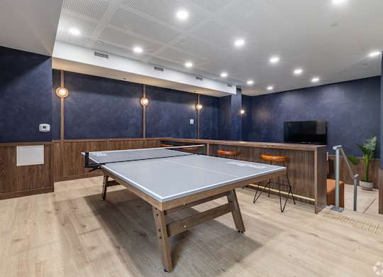 A ping pong table is in the middle of a room with wooden floors and walls.