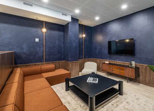 A modern living room with a brown sofa, a black coffee table, and a flat-screen TV mounted on the wall.