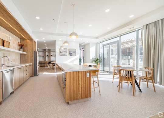 A modern kitchen with wooden cabinets and a dining table.