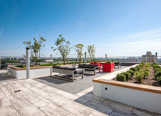 A rooftop patio with a bench, planter boxes, and trees.