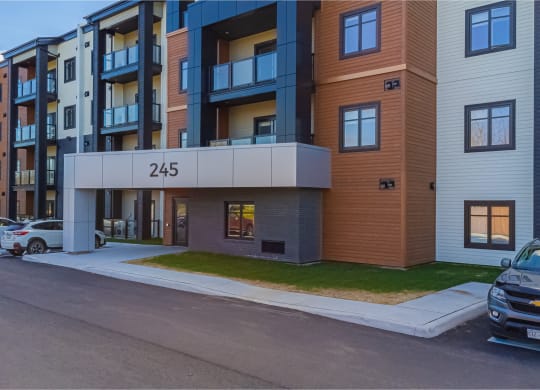 modern apartment building on the corner of a street with cars parked