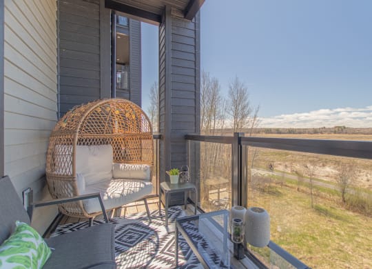 the screened porch has a wickerickericker chair and a view of the water