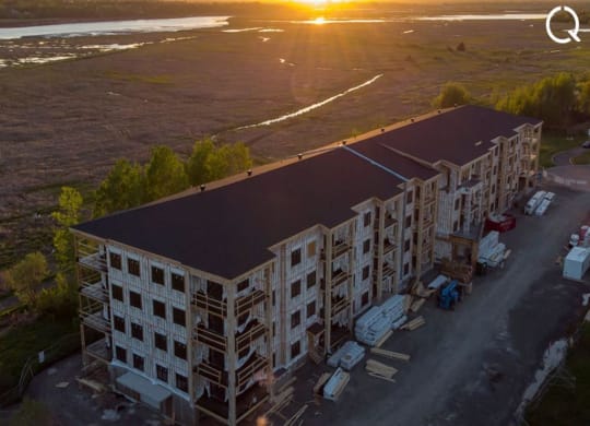 an aerial view of a building with the sun setting in the background