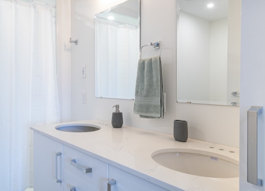 a white bathroom with two sinks and a mirror