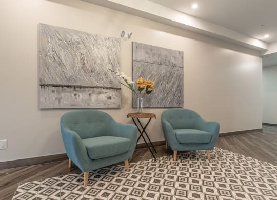 two blue chairs in a room with paintings on the wall