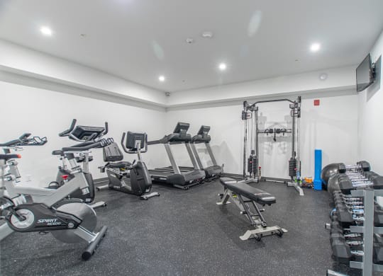 a gym with treadmills and other exercise equipment in a room with white walls