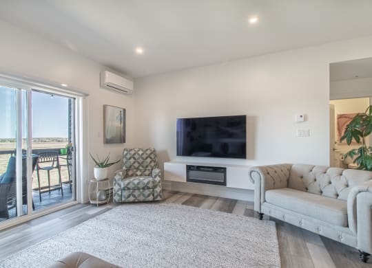 a living room with a couch and a tv and a balcony