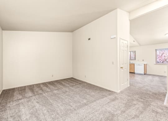 Living room and kitchen of an apartment with carpeting and white walls at Meadowview Apartments, Santa Rosa, CA