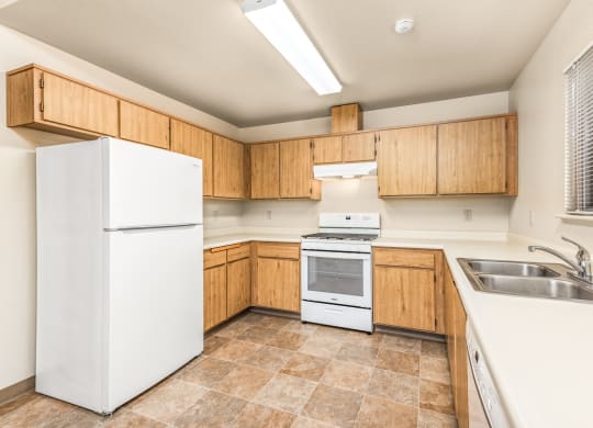 Kitchen with white appliances and wooden cabinets at Meadowview Apartments, Santa Rosa, CA