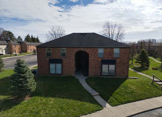 a brick building with a black roof and a sidewalk