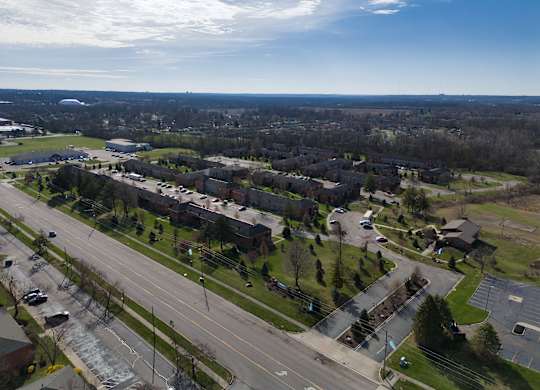 an aerial view of a neighborhood with an empty street and cars on a highway
