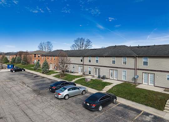 an aerial view of an apartment complex with cars parked in a parking lot