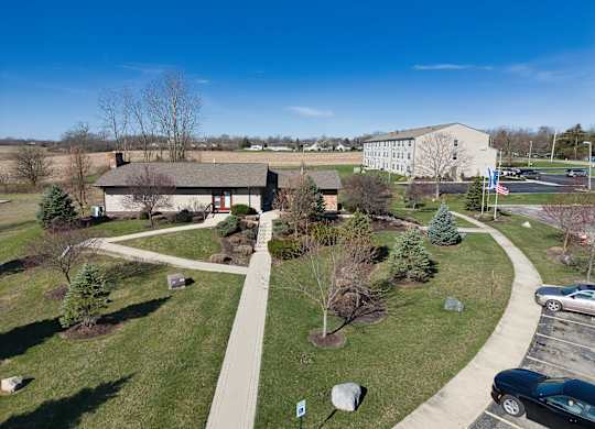 an aerial view of a park with trees and a sidewalk and a building