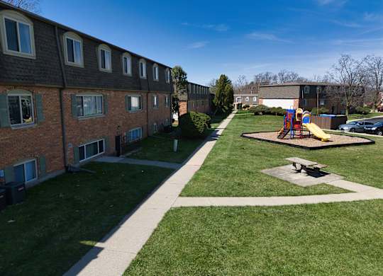 a playground in a yard in front of a brick building