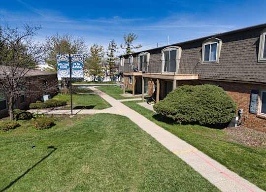 an apartment building with a sidewalk and a blue street sign