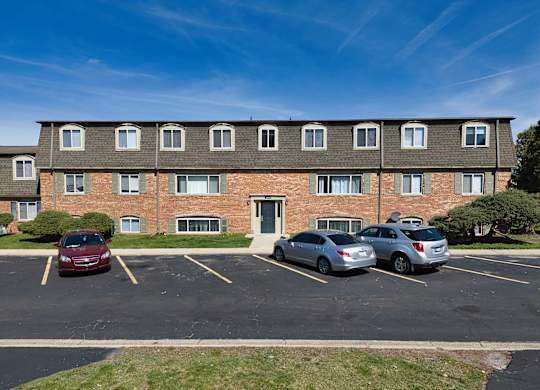 a large brick apartment building with cars parked in a parking lot