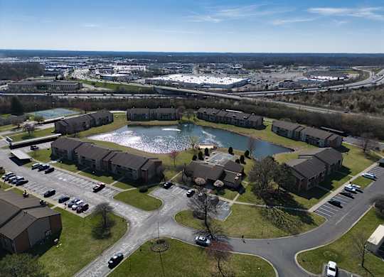 an aerial view of a pond in the middle of a neighborhood with houses and cars