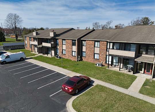 an apartment building with a red car parked in a parking lot
