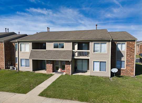 an exterior view of an apartment building with a sidewalk and grass