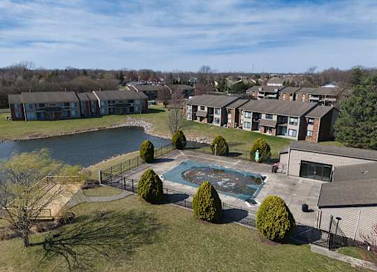 an aerial view of an apartment complex with a swimming pool and a lake