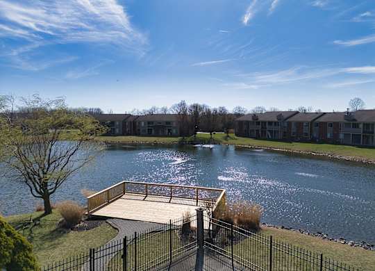 the view of a pond with a bridge in front of an apartment building