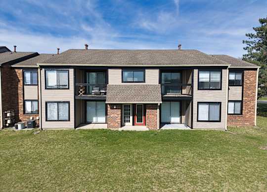 a large apartment building with a lawn and a blue sky