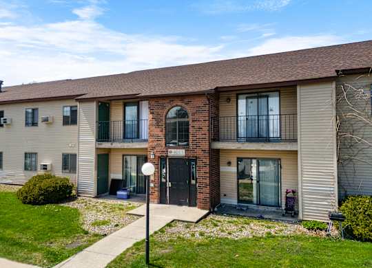 the front of a apartment building with a sidewalk and grass