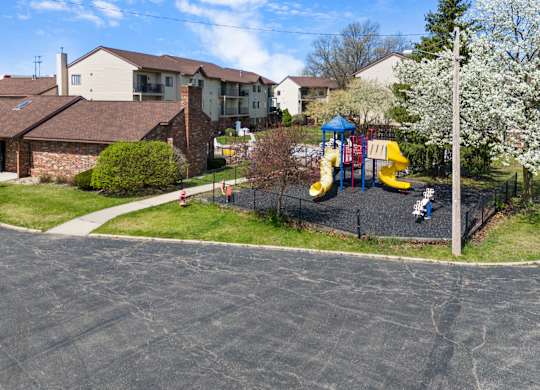 a playground in a neighborhood with houses and children playing on it