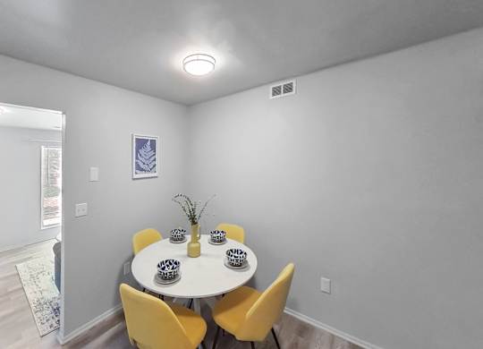 a dining room with a white table and yellow chairs
