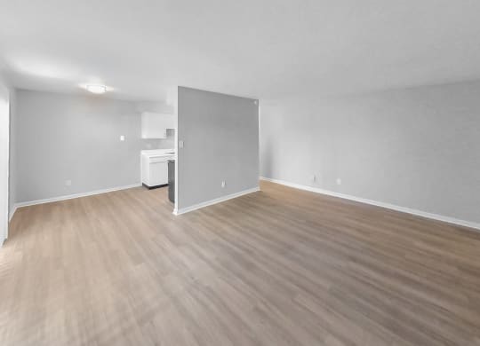 the living room and kitchen of an empty apartment with wood flooring