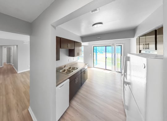 an open kitchen and living room with wood flooring and a door to a balcony