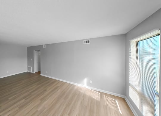 an empty living room with wood flooring and a large window