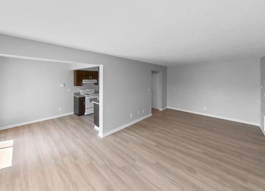 the living room and kitchen of an empty apartment with wood flooring