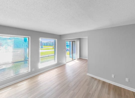 the living room and dining room of an empty house with wood flooring and windows