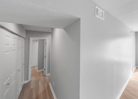 the living room and dining room of an apartment with white walls and wood floors