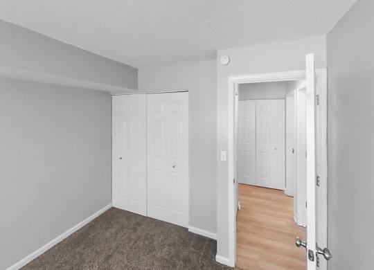 the living room of an apartment with white walls and wood floors