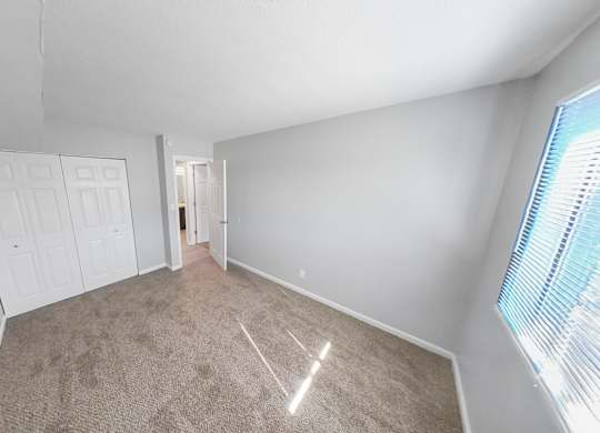 a bedroom with a carpeted floor and a door to a closet