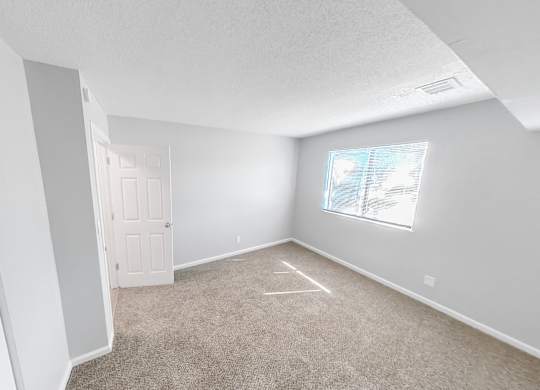 an empty room with carpet and a window