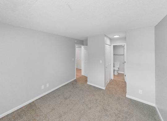 the living room of an apartment with white walls and carpet